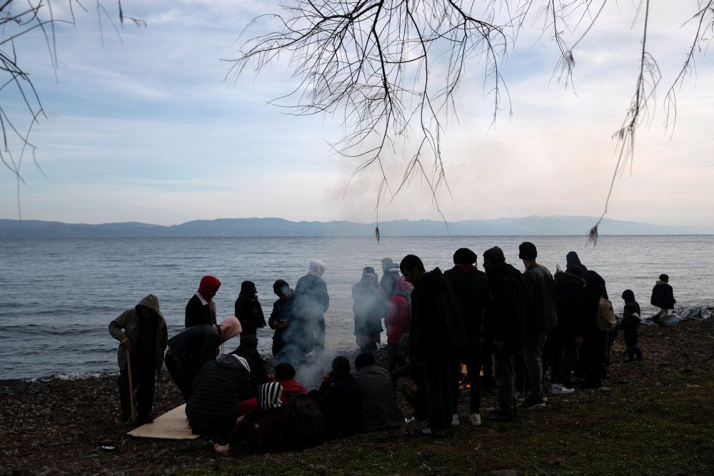 Migranter fra Afghanistan forsøger at få varmen på Lesbos.
