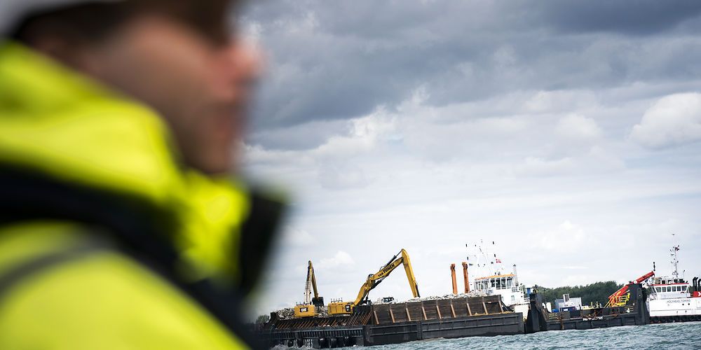 (Arkiv) Tonsvis af sten blev lagt i vandet til en mole ved byggeriet af Femernforbindelsen ved Rødbyhavn i juli. Anlægsarbejder på den tyske side afventer fortsat en retssag.