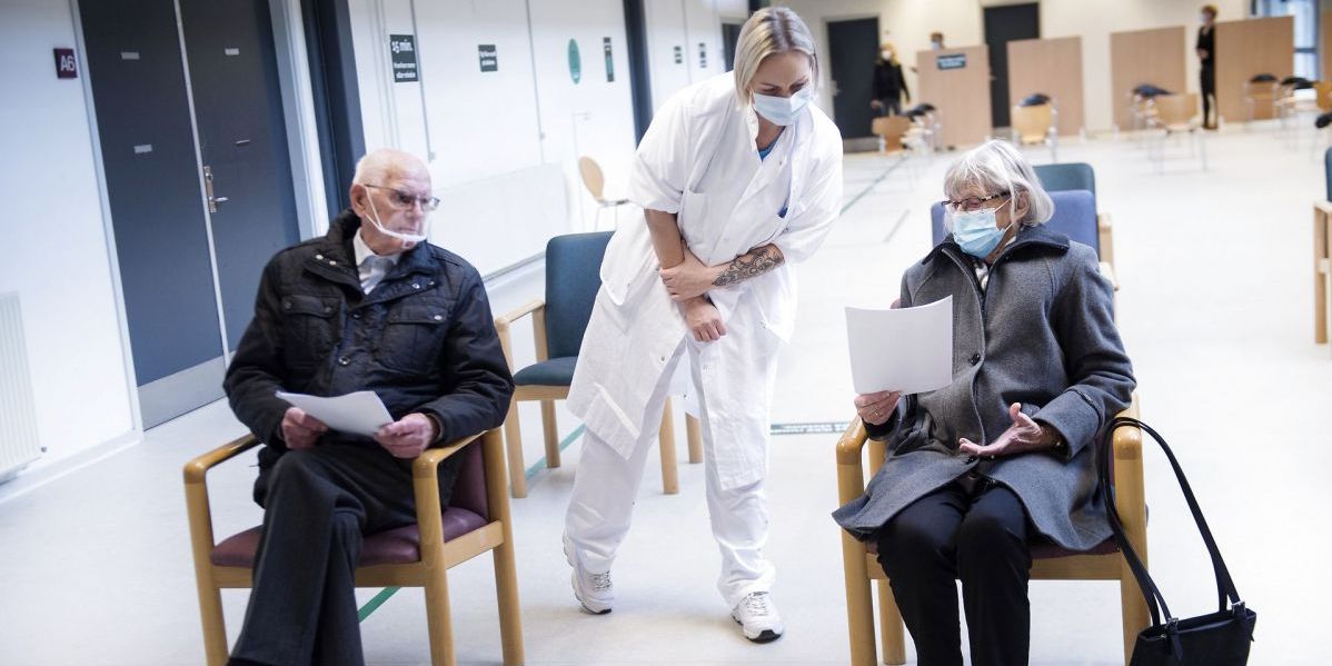 (Arkiv) Førtidspensionister, der er ægtefæller til personale med ekstravagter under corona, bliver trukket i ydelse. Det vil Folketingets partier ændre. På billedet overvåger en social- og sundhedsassistent to ældre, der netop er blevet vaccineret i Odense.