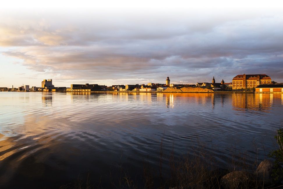 Et konsortium af private investorer ser en god investorcase i Nykøbing Falster og omdannelsen af den gamle erhvervshavn til et levende og rekreativt område. Guldborgsund Kommune indgår derfor et samarbejde med investorerne om et stort byudviklingsprojekt. Her ses havnen fra vandsiden ved solnedgangstid.